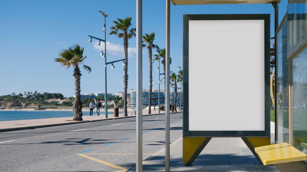 A bus stop right by the beach with pedestrians and palm trees in the background.