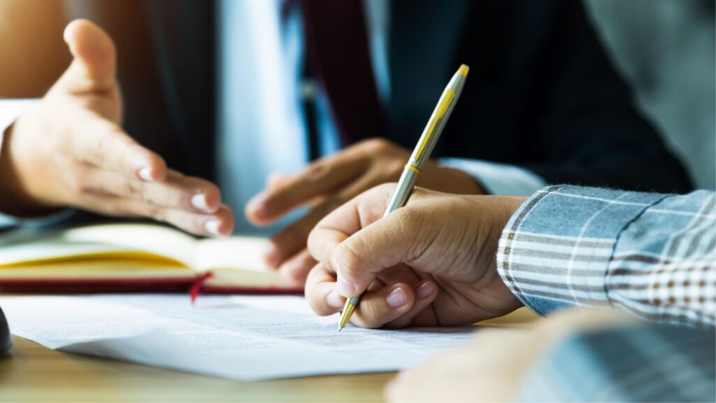 A person signing a document with the help of an attorney.