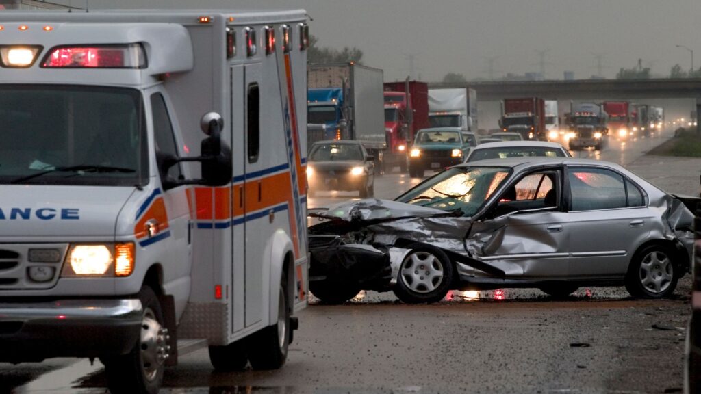 An ambulance at the scene of a car crash on the freeway.