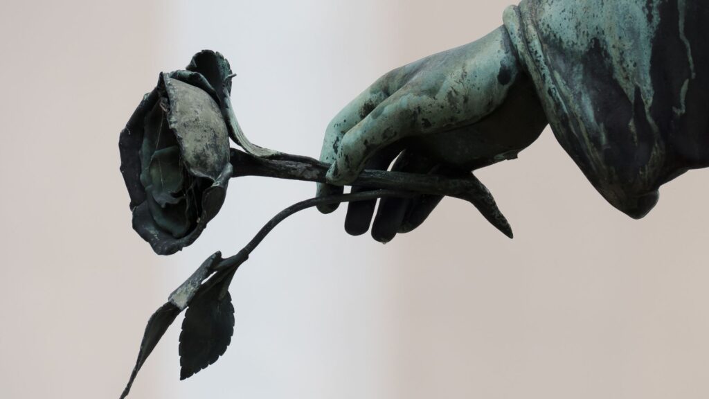 A cemetery statue hand holding a rose.