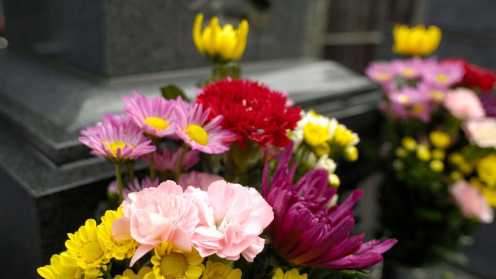Colorful flowers in front of a gravestone.