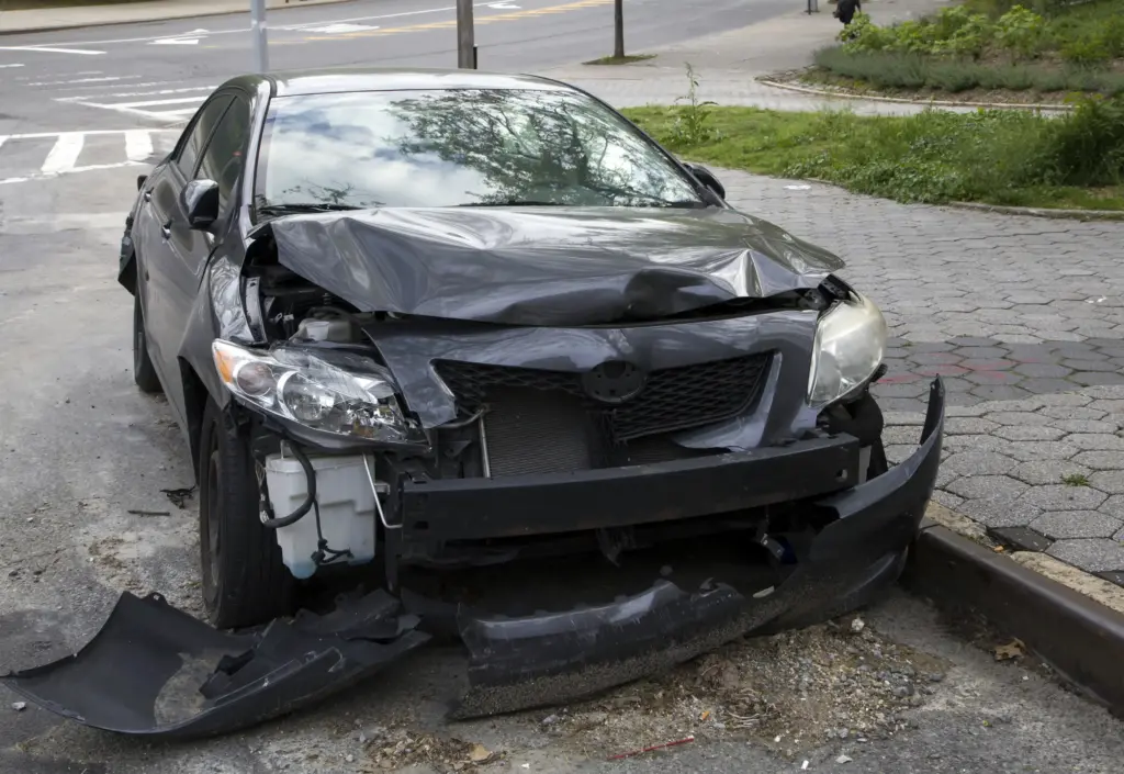 A black car with a busted front bumper.